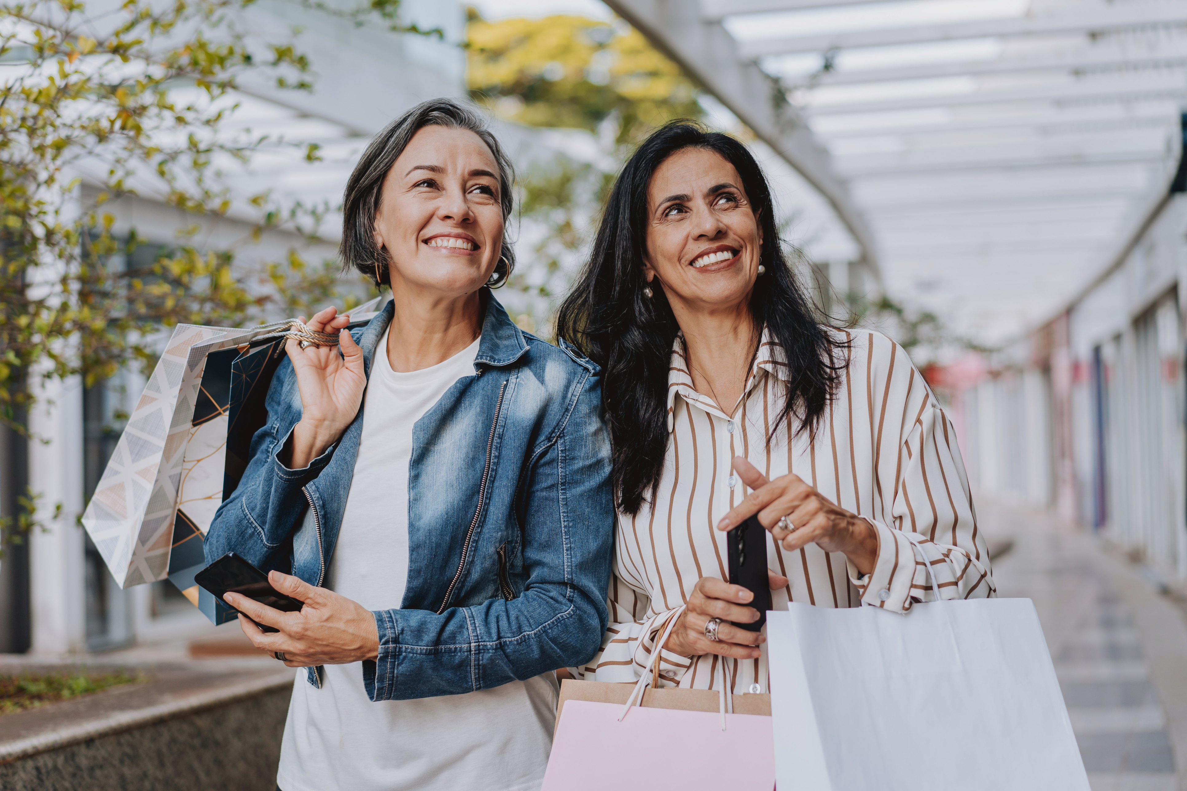 Two mature friends shopping at the mall holding bags