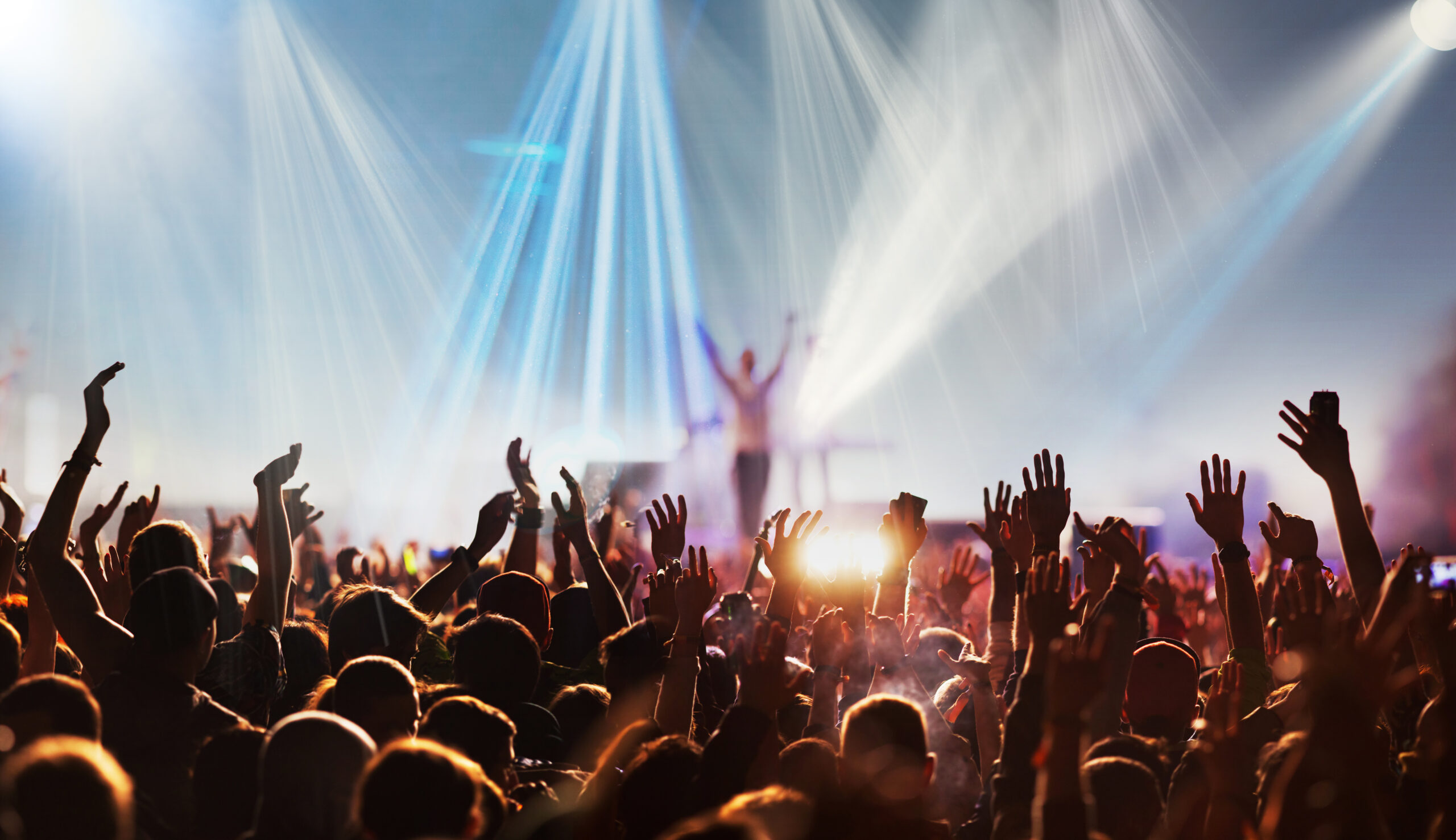 crowd with raised hands at concert festival banner